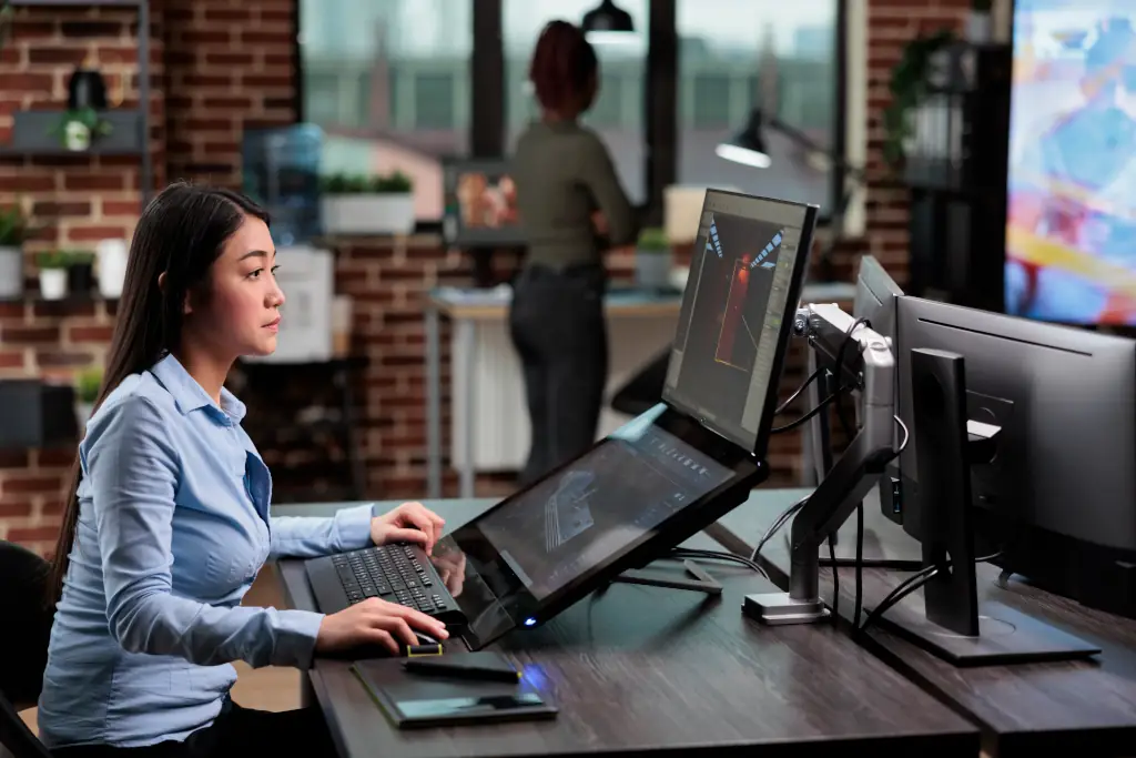 Frau arbeitet am Computer mit Monitorerhoehung und ergonomischer Tastatur