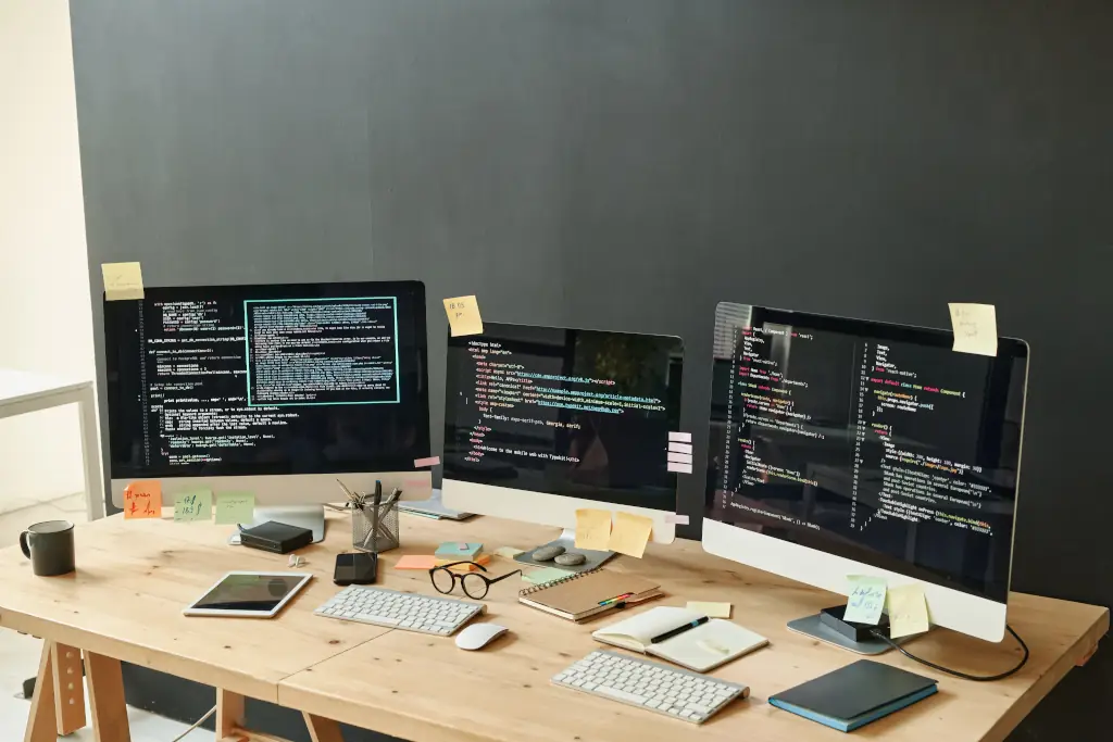 drei Bildschirme am Schreibtisch